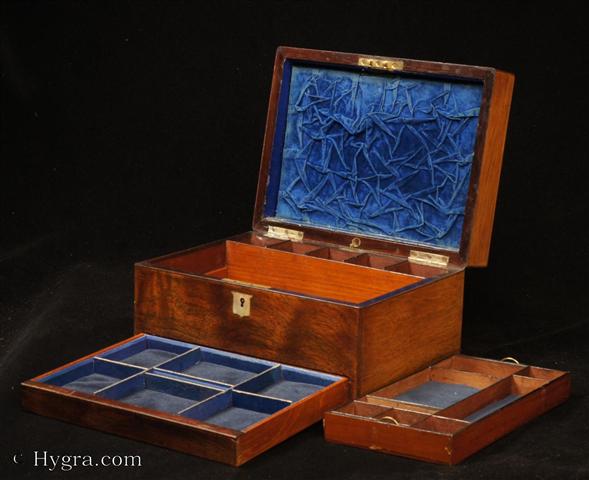 Antique Figured Rosewood box with lift-out compartmentalized tray and sprung drawer fitted for jewelry. There are mother of pearl escutcheons to the top and the front. There is a ruched velvet pad in the lid with mirror framed with gold embossed leather  behind.  It is released by pressing behind the lock catch. The sprung drawer is released by pressing on a button in the centre of the back facing. The lift-out tray  is of mahogany construction with rosewood facings. New pads of velvet have been made to make the tray suitable for jewelry. There is further space beneath. Circa 1850.-Enlarge Picture